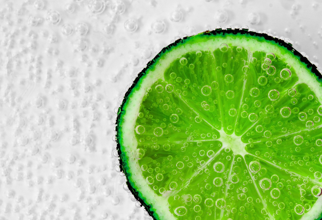 A green slice of fruit, possibly a lime, floating amid bubbles