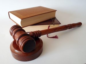 Judge's gavel with nondescript books in the background, brown covers with the pages facing the viewer, two of the stacked on one another, plain white background