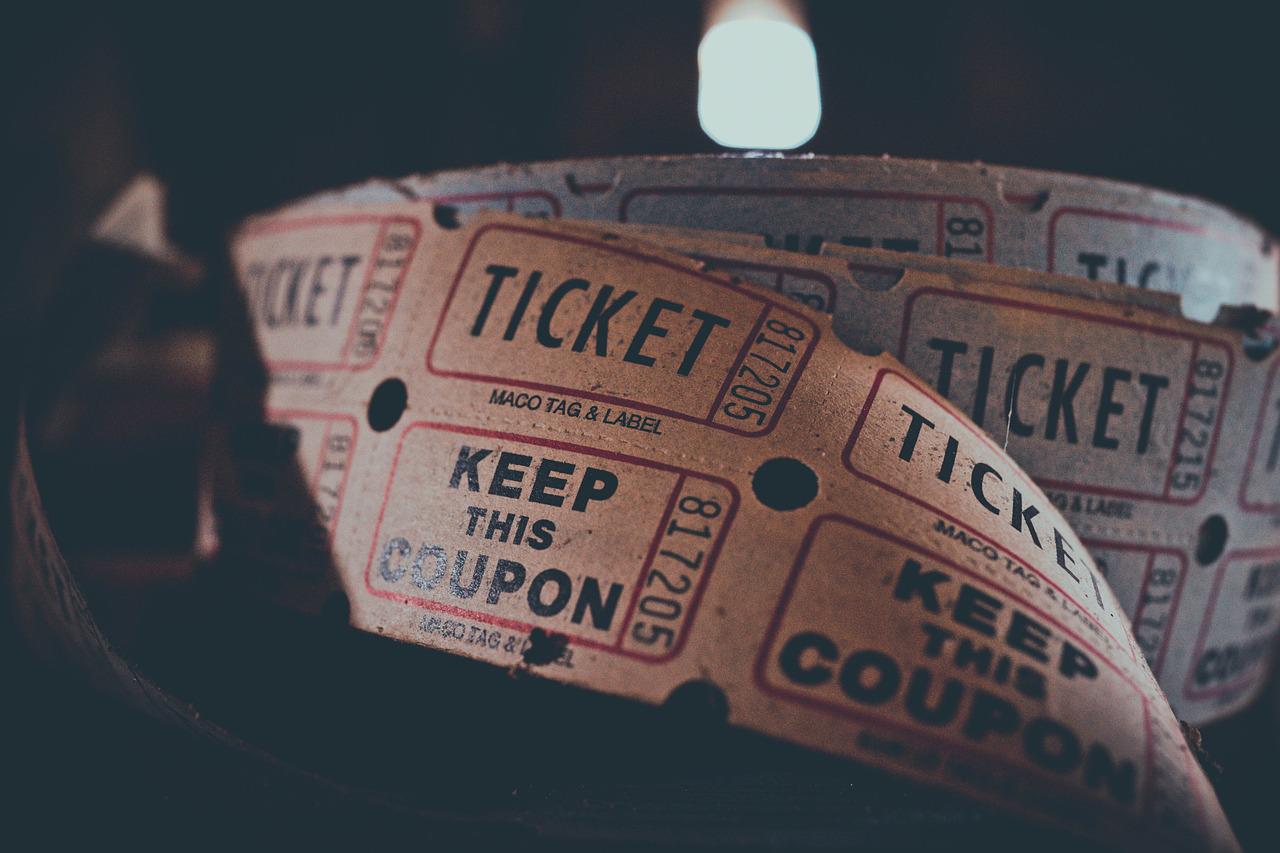 A roll of tickets unravelling with a dark background, slightly orange with dark print