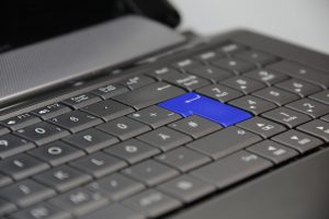 A black laptop keyboard with white lettered keycaps and a blue enter key.