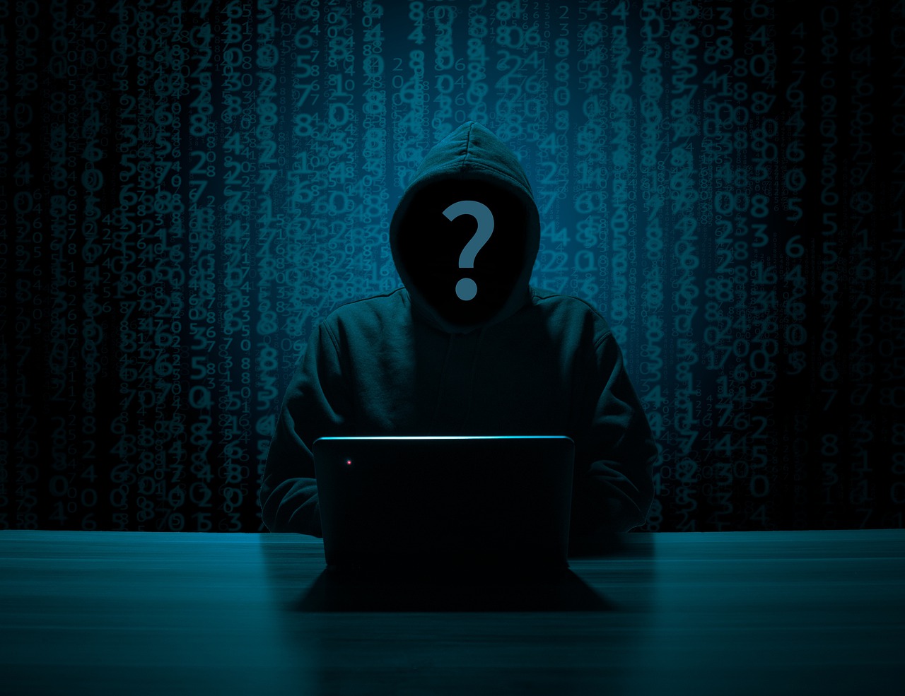 hoodie hacker sitting in front of a laptop with a monochrome blue background, laptop has a single red light on it