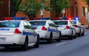 A series of four Baltimore police cars in a row on a street during the daytime